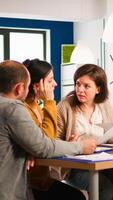 Diverse businesspeople brainstorming while meeting together at company office sitting at desk holding documents. Colleagues working planning success financial strategy discussing in modern office. photo