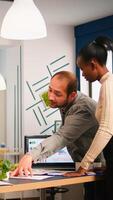 Diverse business people communicating in start up business office standing over desk looking through financial documents. Multiethnic team analysing company informations in modern workplace photo