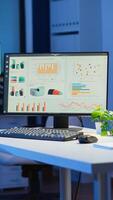 Empty start up business office with modern design during night with graphics running on the desktop. Financial company with nobody in it, place of work startup, workplace indoors concept photo