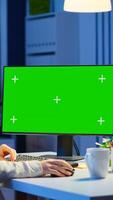 Woman looking at computer with chroma key during night time in start up business office working overtime. Freelancer watching desktop monitor mockup display with green screen, typing writting photo