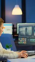 Videographer working at computer from business office, editing and audio footage at night. Content creator using professional device modern technology network wireless processing film montage. photo