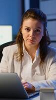 Tired woman manager raising head looking at camera sighing after typing on laptop, working late at night in start-up business office. Focused employee using technology network wireless doing overtime photo