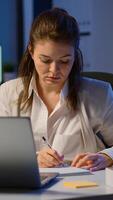 Business woman working overtime to respect deadline of project sitting in business office typing on laptop late at night. Busy focused employee using modern technology network wireless searching photo