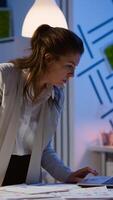Happy business woman working on financial reports pointing to numbers, looking at laptop checking statistics graphs, having good results, smiling standing at desk late at night doing overtime. photo
