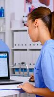 Doctor assistant checking list diagnosed of patients, writing on clipboard with x-ray and medical equipment around. Physician working in hospital making appointments and analysing patient registration photo