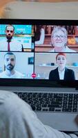 Focused adult using laptop computer during videocall conference talking about social business connection while sitting on couch. Relaxed man working at online communication project overtime in kitchen photo