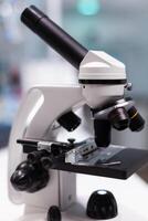 Close up of microscope in biochemistry laboratory at research clinic. Scientific instrument with magnifying glass lens and transparent tray for substance examination in cabinet photo
