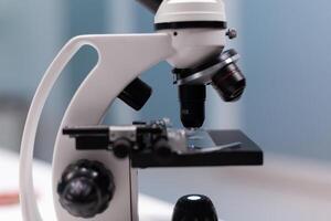 Close up of chemical microscope with magnifying glass for microbiology experiment and development in science laboratory. Instrument with lens and glass tray for dna sample analysis photo