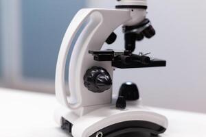 Close up of microscope with magnifying glass for biochemistry research experiment in science laboratory. Instrument with lens and glass tray for dna sample examination and healthcare photo