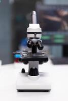 Close up of professional microscope in laboratory space used for science experiment with substance. Tool with magnifying glass lens and transparent tray for biology lab discovery photo