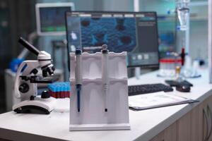 Nobody in research laboratory with micro pipette on desk. Empty scientific development place with microscope and chemical equipment and lab glassware. Biochemistry cabinet with tools photo