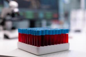 Close up of vacutainers with blood for dna research in laboratory. Glass tubes on tray filled with substance for testing and analysis. Transparent flasks with liquid in biochemistry cabinet photo