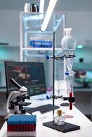 Science laboratory equipment and test tube with blood for healthcare development. Chemical dripping pipe with glass flask for analysis in biochemistry lab at clinic. Professional instruments photo