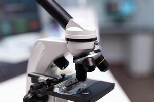 Close up of microscope with transparent tray in science laboratory. Microbiology instrument with magnifying glass and optical lens for research development. Chemical tool in lab photo