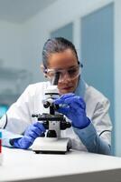 Scientist doctor analyzing blood sample using microscope searching for healthcare treatment developing virus vaccine during medical experiment. Chemist researcher working in hospital laboratory photo