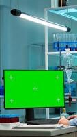 Female research scientist has conversation with man bioengineer next to a desktop computer with green screen mock up. They look at chroma key pc template in a modern science laboratory. photo
