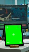 Scientist standing at monitor in background analysing virus evolution while tablet with mock-up green screen working in front. Man lab researcher examining vaccine developent bringing blood samples photo
