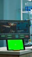 Tablet with green screen working in labooratory with mock up, chroma key display while professional engineer testing virus evolution in background. High tech development lab with blood samples photo