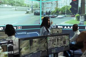 Indian woman team leader guides her staff to monitor surveillance footage in monitoring room, tracking speed limits for public safety via satellite CCTV system. Operates on screen in control center. photo