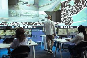 Middle eastern manager overseeing his staff order tracking activity, instructing operators to update customers on parcel shipment progress. Delivery agency monitoring their trucks in traffic. photo