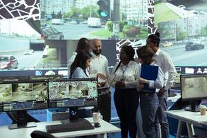Team of diverse operators uniting forces to ensure express shipping, finding new routes to avoid urban traffic. Agency operating on CCTV security cameras footage and gps navigation. photo