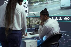Indian employee consulting his african american team leader on cargo logistics insight, discussing about improving express shipment by using gps coordinates on satellite map, order tracking. photo