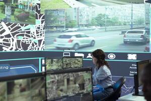 Diverse employees working on examining real time surveillance footage to find irregularities within urban traffic dynamics. Agency workers monitoring on CCTV system for intelligence. photo
