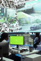 African american woman operator monitoring couriers in traffic via CCTV footage, using an isolated screen in control center. Dispatch employee uses gps coordinates to track cars. photo