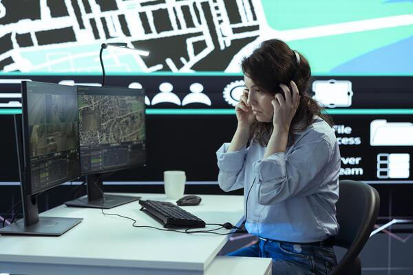 Woman operator works in call center to ensure fast order delivery to clients, handling any delay complains. Employee finding alternative routes for couriers to avoid heavy traffic via radar.