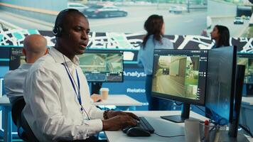 African american dispatch operator gives directions and gps coordinates of the location to the delivery truck driver, following the orders on satellite map. Employee monitors traffic. Camera B. photo