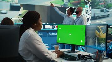 African american operator works with isolated display and satellite map, guiding the delivery truck driver to arrive at shipment location pin. Employee helps with heavy traffic on CCTV. Camera B. photo