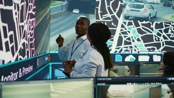 African american team monitoring routes and directions on satellite map, guiding delivery trucks to avoid traffic and ship orders faster. Operators consulting radar surveillance system. Camera B. photo