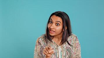 Upset indian person fighting with friend, doing scolding gesturing, isolated over studio backdrop. Annoyed woman arguing with opponent during discussion, doing admonishing hand gestures, camera B photo