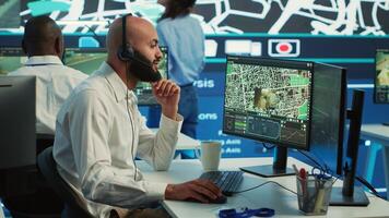 Middle eastern call center operator gives directions to the courier, avoid traffic by monitoring radar CCTV surveillance and a satellite city map. Employee helps with express delivery. Camera A. photo