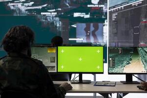 Army soldier uses satellite CCTV footage and a green screen in federal control center, collecting intelligence and detecting enemy ships. IT operator at government defense agency. photo