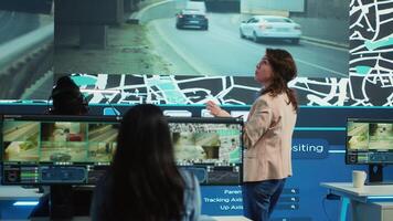 Manager supervising diverse employees operators in delivery call center office, people using global positioning system to guide shipment cars on city routes via satellite navigation map. Camera A. photo