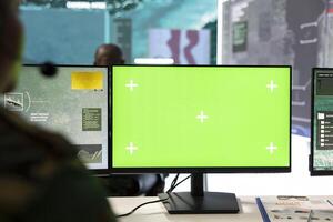Army recruit operates on surveillance imagery and green screen, monitoring battlefield satellite data on a pc in power base. Soldier IT engineer employs reconnaissance system. photo