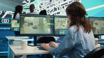 Diverse team of employees monitoring delivery trucks routes around the city with map and surveillance footage. People working with gps coordinates for tracking orders, cargo logistics. Camera B. photo