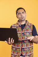 Portrait of man shocked after seeing error message on laptop screen while doing job tasks, studio background. Worker with perplexed facial expression, confused by mail received on notebook photo