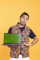 Portrait of tech professional pointing finger towards green screen laptop, isolated over studio backdrop. Content creator doing technology reviews, presenting mockup notebook photo