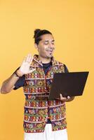 Smiling man doing waving hand gesture, catching up with friend over online videocall on laptop. Upbeat person saluting mate on videoconference using notebook device, studio background photo