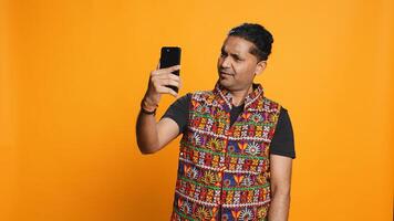 Happy man chatting with friend over online videocall on smartphone, doing friendly gestures. Smiling person communicating with mate on teleconference using mobile phone, studio background, camera B photo