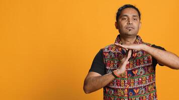 Serious man requesting timeout, doing hand gestures, unable to continue concept. Bold person doing insistent pause sign gesturing, desiring break, isolated over studio background photo