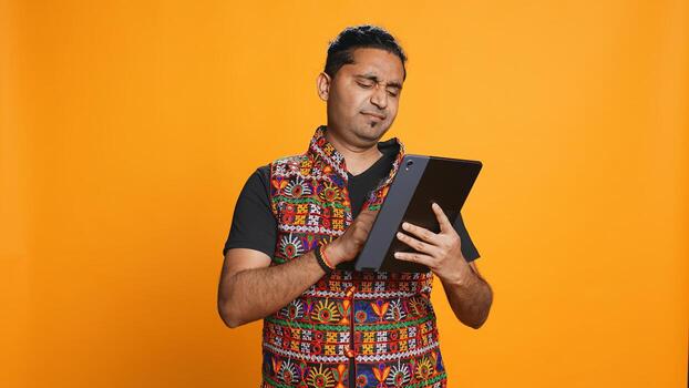 Man upset after lacking necessary money while trying to buy stuff online on tablet. Sad person looking at debit card after getting transaction rejected on device, studio background, camera B photo