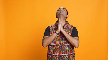 Indian man putting hands together in begging gesture, making wish, isolated over studio background. Faithful person asking for something, praying and hoping, believing in higher power, camera B photo