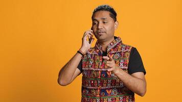 Indian man discussing with best friend over telephone call using smartphone. Cheerful person talking with mate in phone call using cellphone, isolated over studio background, camera A photo