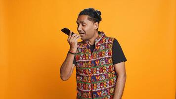 Irked indian man fighting with friends during telephone call, isolated over studio background. Outraged person arguing with mates during conversation on mobile phone, camera B photo