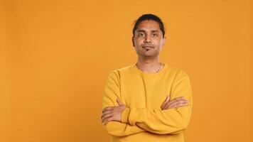 Portrait of cheerful friendly indian man smiling, looking pleased, isolated over yellow studio background. Happy expressive asian person grinning, feeling satisfied, camera A photo
