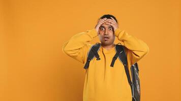 Overloaded delivery man carrying huge stack of pizza boxes, worried after making mistake. Worker encumbered by too many food orders, dropping them, feeling upset, studio background, camera A photo