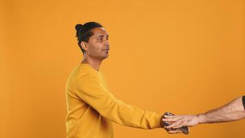 Friendly upbeat pizza delivery employee giving takeaway order to client paying with credit card. Asian man offering food order and digital payment method to customer, studio background, camera A photo